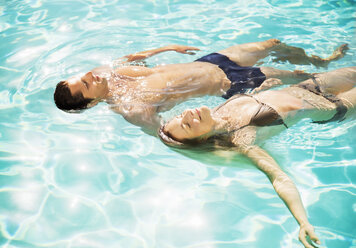 Couple floating in swimming pool - CAIF07721