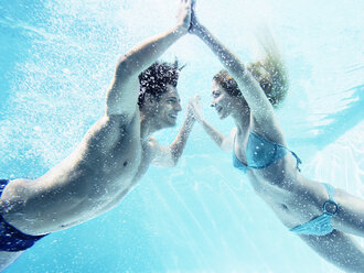 Couple touching hands underwater - CAIF07762