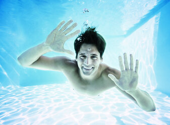 Porträt eines lächelnden Mannes unter Wasser im Schwimmbad - CAIF07765