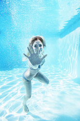 Portrait of smiling woman underwater in swimming pool - CAIF07767