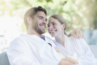 Couple in bathrobes hugging at spa - CAIF07813