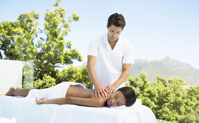 Frau erhält Massage auf der Terrasse eines Spas - CAIF07842