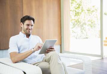 Man using digital tablet in armchair - CAIF07852