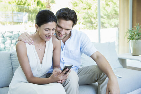 Ehepaar benutzt Handy auf Sofa - CAIF07855