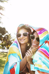 Happy friends wrapped in towel standing against clear sky - CAVF01369