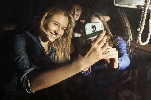 Glückliche Freunde, die ein Selfie machen, während sie im Auto sitzen - CAVF01371