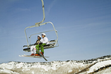 Skifahrer im Skilift sitzend gegen klaren Himmel - CAVF01408