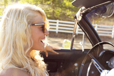 Cheerful woman sitting in convertible car - CAVF01421