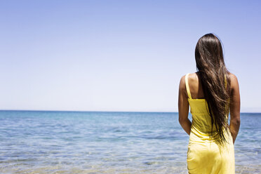 Rear view of woman standing at shore against sea - CAVF01454