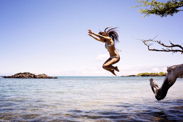 Woman jumping in sea against clear sky - CAVF01456