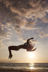 Woman backflipping against sky during sunset - CAVF01474