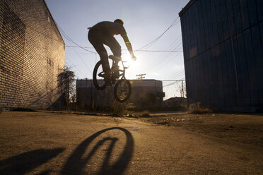 Rückansicht eines springenden Mannes beim Radfahren auf der Straße - CAVF01500