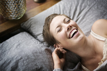 Hohe Winkel Ansicht der Frau lachend, während auf dem Bett zu Hause liegen - CAVF01516