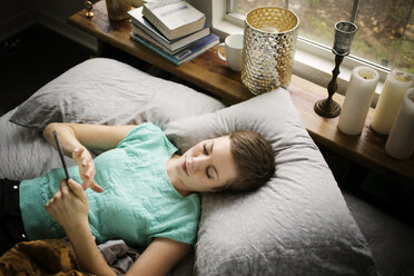 Hohe Winkel Ansicht der Frau mit Smartphone, während auf dem Bett liegend zu Hause - CAVF01519