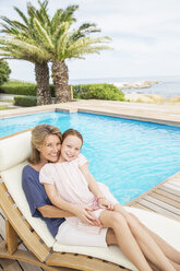 Großmutter und Enkelin entspannen sich am Pool - CAIF07928