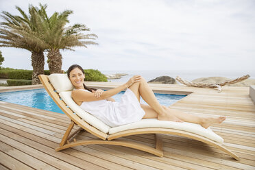 Frau entspannt im Liegestuhl am Pool - CAIF07930