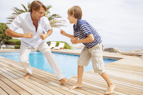 Vater und Sohn spielen am Pool - CAIF07963