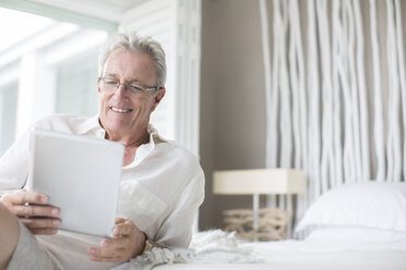 Älterer Mann benutzt digitales Tablet auf dem Bett - CAIF07969