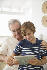 Older man and grandson using digital tablet - CAIF07975