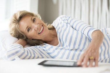 Older woman using digital tablet on bed - CAIF07980