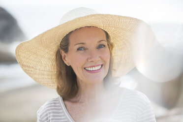 Older woman wearing straw hat on beach - CAIF07989