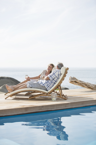 Älteres Paar entspannt am Pool, lizenzfreies Stockfoto