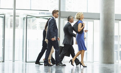 Business people walking in office lobby - CAIF08010