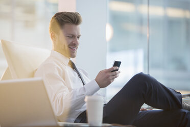 Businessman using cell phone in office - CAIF08037