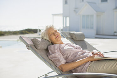 Ältere Frau schläft auf einem Liegestuhl am Pool - CAIF08054
