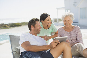 Family using digital tablet at poolside - CAIF08056