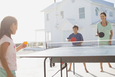 Familie spielt gemeinsam Tischtennis vor dem Haus - CAIF08057