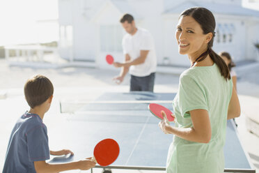 Familie spielt gemeinsam Tischtennis im Freien - CAIF08060