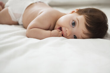 Baby girl laying on bed - CAIF08063