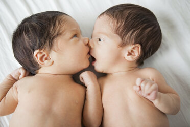 Twin baby girls kissing on bed - CAIF08072