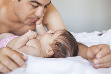 Vater bewundert kleines Mädchen auf dem Bett - CAIF08074