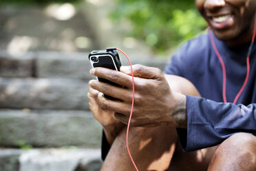 Mittelteil eines Mannes, der beim Sport ein Smartphone benutzt - CAVF01555