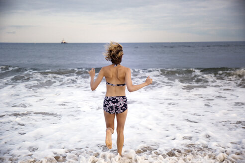 Rückansicht einer Frau, die am Strand läuft - CAVF01581