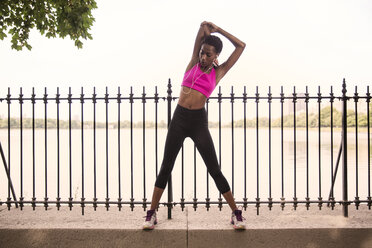 Woman exercising against river in city - CAVF01598