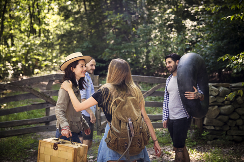 Glückliche Freunde mit Gepäck auf dem Feld stehend, lizenzfreies Stockfoto