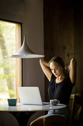 Woman using laptop computer while sitting at table - CAVF01650