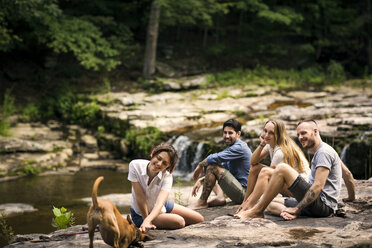 Freunde mit Hund entspannen sich auf einer Felsformation im Wald - CAVF01654