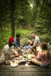 High angle view of friends eating food while sitting porch in forest - CAVF01657