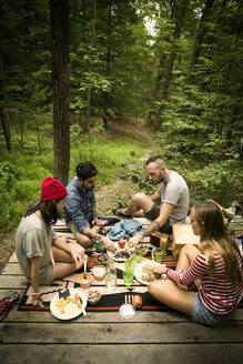 Hoher Blickwinkel von Freunden, die auf einer Veranda im Wald sitzen und etwas essen - CAVF01657