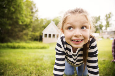 Girl looking away while kneeling on field in backyard - CAVF01685