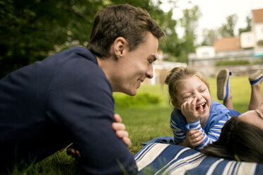 Father looking at kids lying on field - CAVF01691