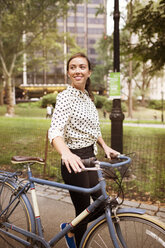 Frau schaut weg, während sie mit dem Fahrrad auf der Straße im Central Park spazieren geht - CAVF01718