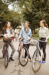 Friends with bicycles standing on road in central park - CAVF01719