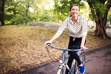 Woman looking away while cycling in central park - CAVF01723