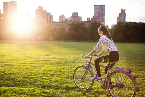 Side view woman cycling in Central Park in city - CAVF01739