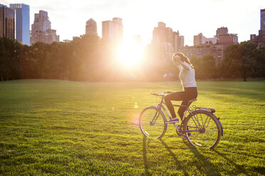 Woman with arms outstretched cycling in Central Park - CAVF01740